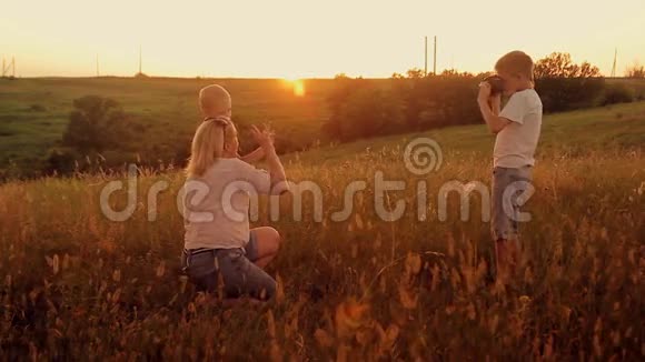 一家人在日落时在田野里拍照妈妈和两个儿子在度假时自拍视频的预览图