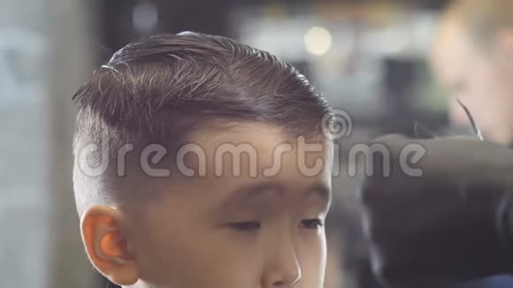 戴着黑色手套的理发师在一个60英尺高的亚洲孩子的头发上扎了一个发夹视频的预览图