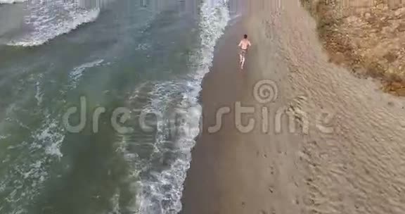 早上慢跑的家伙沿着海边的冲浪线在夏天视频的预览图