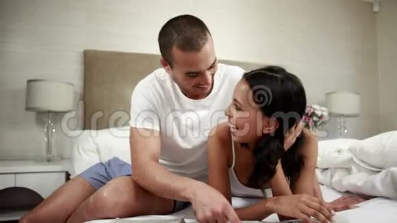 一对恩爱的夫妇在床上讨论视频的预览图
