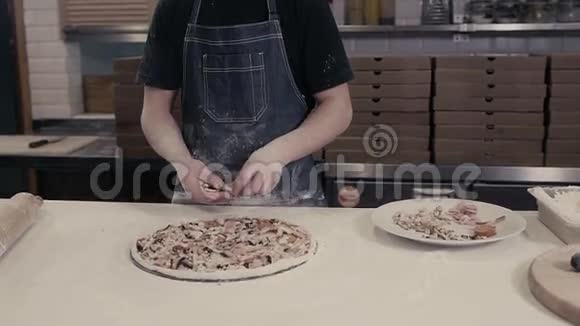 身着蓝色制服的厨师面包师的特写手在厨房里做披萨视频的预览图