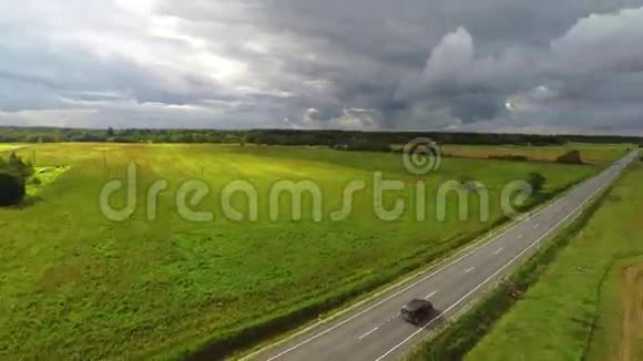 汽车驶往地平线绿色的田野和云彩空中镜头视频的预览图