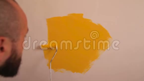 建筑工人和专业油漆工使用油漆滚筒刷油漆墙壁黄色视频的预览图