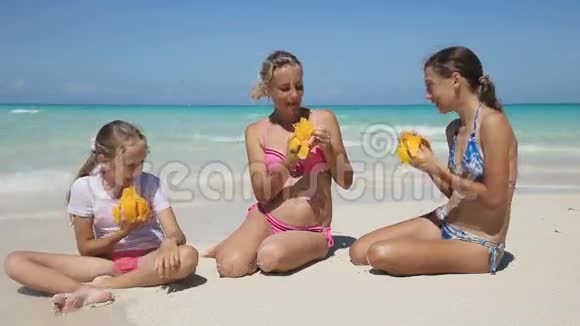 一家人在海滩上吃芒果水果视频的预览图