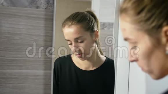 脸上长痘的女孩是镜子旁边的浴室视频的预览图