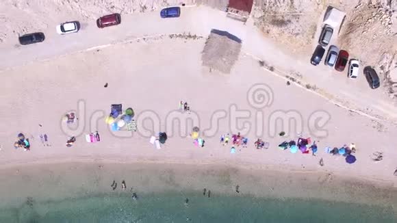 在帕格岛沙滩上停着车和人的上空飞行视频的预览图