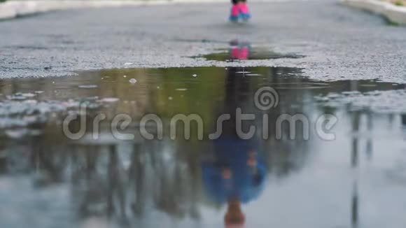 穿运动鞋的跑步者的腿的特写镜头女运动员在公园里慢跑踩在泥泞的水坑里视频的预览图