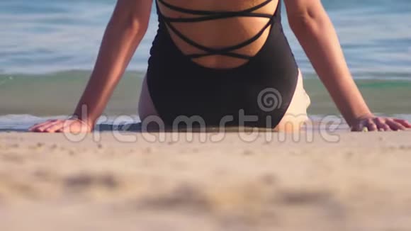 穿着黑色泳衣在白色沙滩上的女孩美丽的模特在海边沐浴阳光视频的预览图