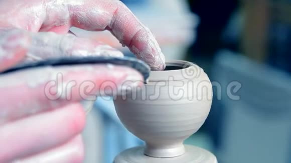 女子双手托着壁壶用陶泥在圆圈上雕刻出来视频的预览图