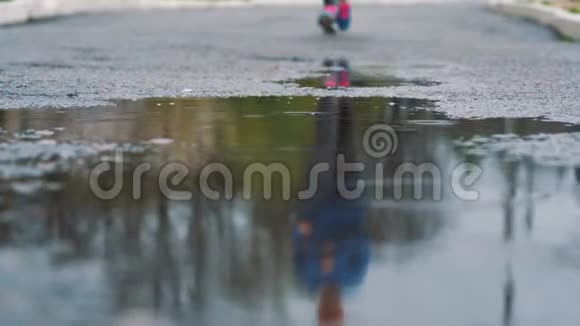 穿运动鞋的跑步者的腿的特写镜头女运动员在公园里慢跑踩在泥泞的水坑里视频的预览图