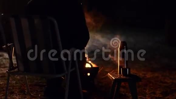 女人坐在篝火前喝茶用滑块射击视频的预览图