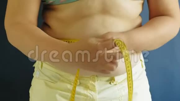 蓝色背景下的胖女人腹部特写视频的预览图