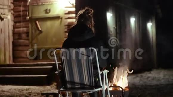 女人坐在篝火前喝茶用滑块射击视频的预览图