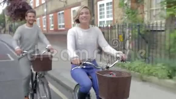 一对夫妇一起骑自行车沿着城市街道视频的预览图