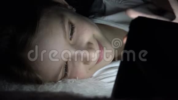 儿童在黑暗中玩平板电脑女孩在床上浏览互联网而不是睡觉视频的预览图