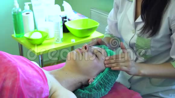 一个年轻的女孩在一个接待与美容师美容师正在准备洗脸脸部按摩视频的预览图