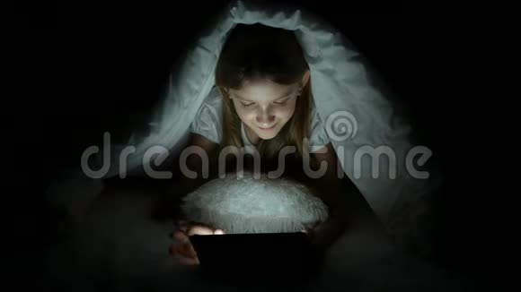 儿童在黑暗中玩平板电脑女孩在床上浏览互联网而不是睡觉视频的预览图