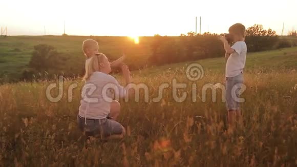 一家人在日落时在田野里拍照妈妈和两个儿子在度假时自拍视频的预览图