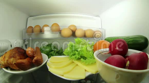 在冰箱里找食物的人肉或蔬菜之间的选择视频的预览图