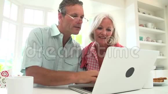 中年夫妇看着笔记本电脑吃早餐视频的预览图