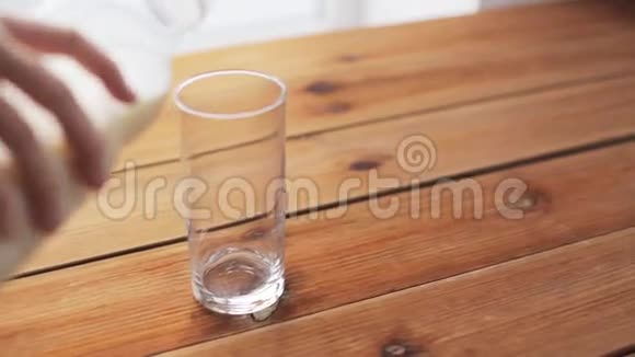 用手将牛奶倒入木桌上的玻璃中视频的预览图
