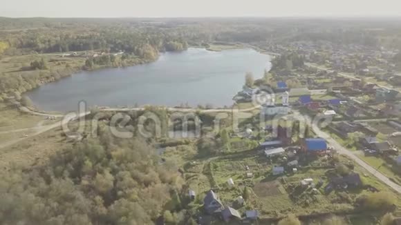 鸟瞰靠近池塘的欧洲村庄美丽的鸟瞰彩色湖和村庄与教堂顶部视图视频的预览图
