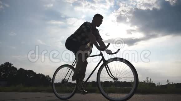 年轻人骑着老式自行车的剪影背景是美丽的日落天空在乡下骑自行车视频的预览图