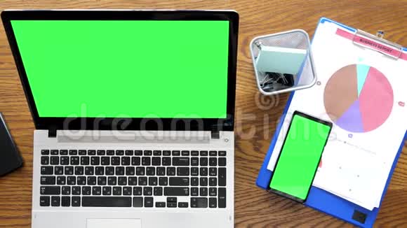 桌面上有绿色屏幕的笔记本电脑和智能手机视频的预览图