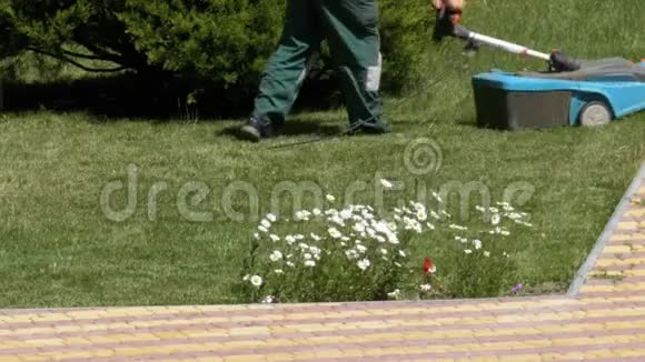 携带便携式电动割草机的人在公园草坪上割草视频的预览图