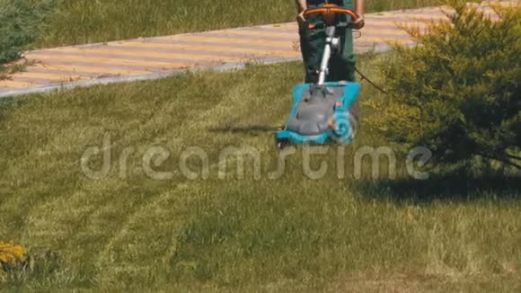 携带便携式电动割草机的人在公园草坪上割草视频的预览图