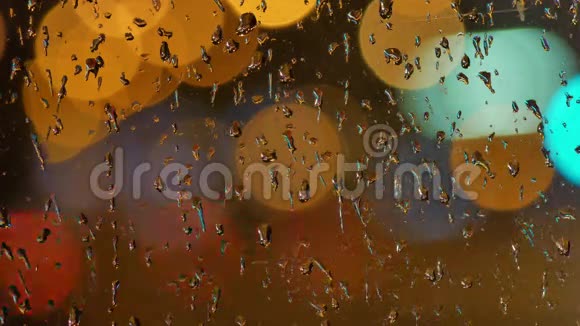 夜晚的交通灯在雨滴中透过玻璃模糊背景在夜晚移动波克圈视频的预览图
