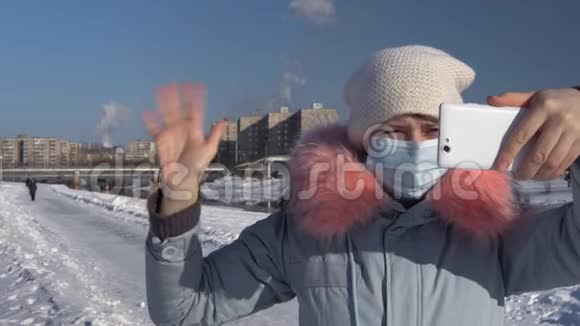 一个女人戴着面罩在冬天抽烟斗的背景下视频的预览图
