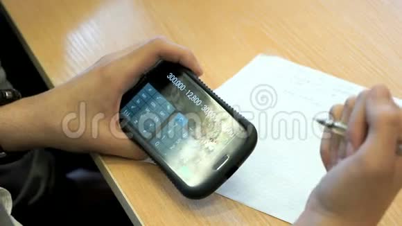 坐在书桌前的学生拿着手机视频的预览图