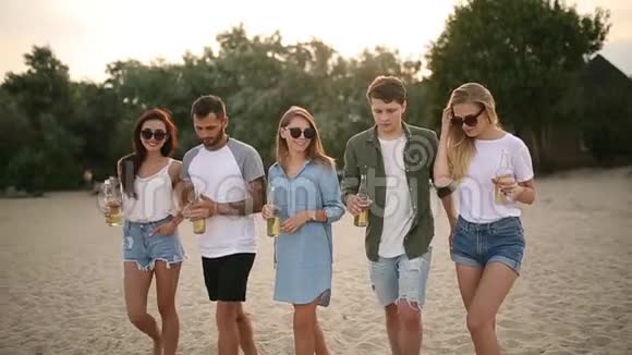 一群朋友在日落时分在海滩上玩着享受饮料和放松的乐趣男女青年视频的预览图