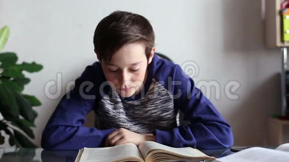 十几岁的男孩在家里的桌子上看书视频的预览图