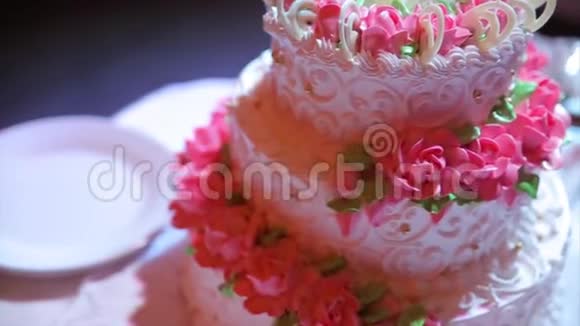 一个多层次的白色婚礼蛋糕在一个银色的底座和粉红色的花在上面视频的预览图