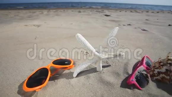 沙滩上的太阳镜贝壳海星和拖鞋视频的预览图