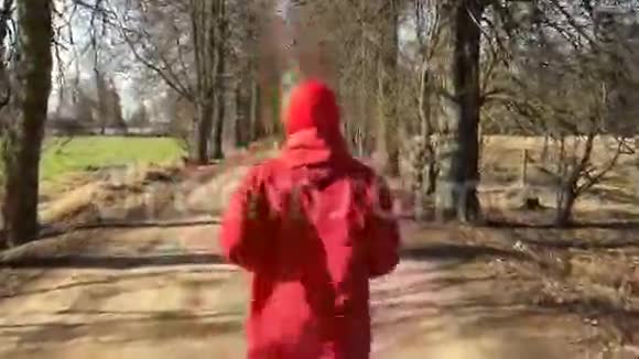 穿红色衣服的运动员跑在公园小巷里镜头跟着他视频的预览图