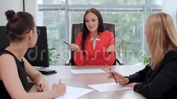 三个穿着商务套装的年轻漂亮女人坐在办公桌前讨论工作流程主管和下属视频的预览图