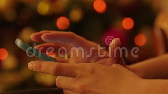 圣诞树旁的女士双手智能手机视频的预览图