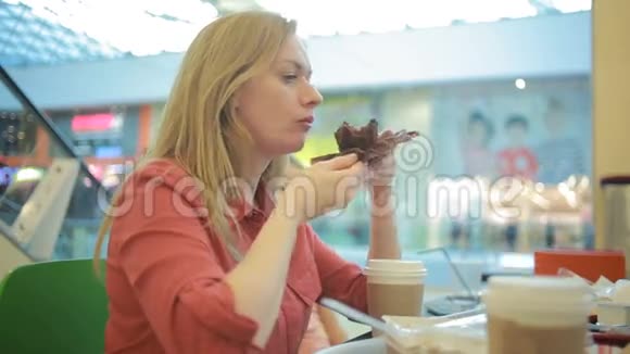 一个胖女人在咖啡馆里吃蛋糕然后啜饮咖啡视频的预览图