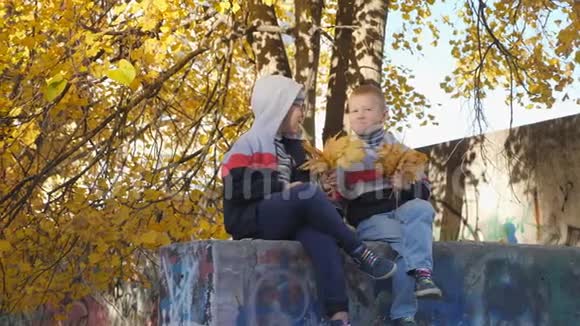 秋天黄色叶子里的小孩子孩子们在街上玩落叶桦树和秋树林视频的预览图
