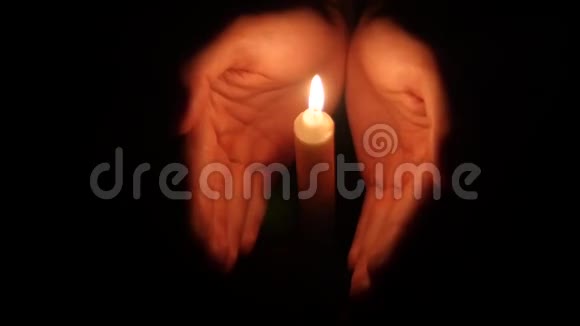 双手在黑暗中举起燃烧的蜡烛视频的预览图