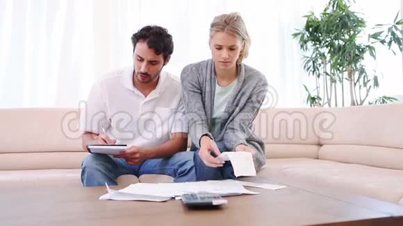 一对夫妇坐在沙发上检查账单视频的预览图