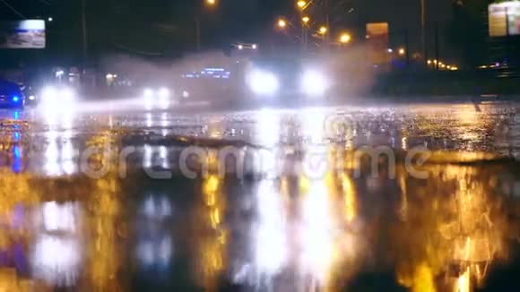 汽车驶进城市夜路上的大水坑里水坑从汽车的车轮下散落出来视频的预览图