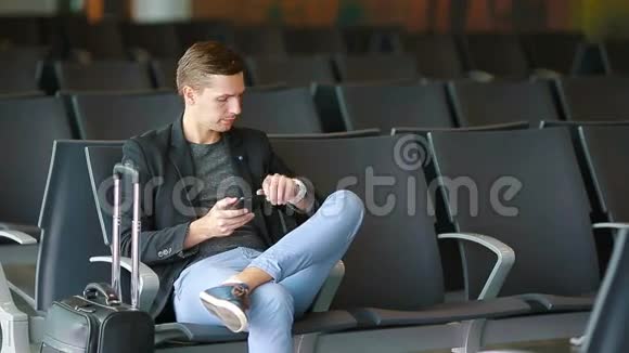 城市商人在机场里用智能手机说话穿西装外套的休闲青年商人视频的预览图