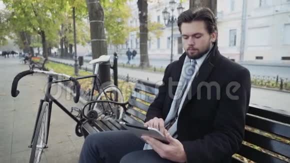 商人用平板电脑坐在靠近自行车的长凳上视频的预览图