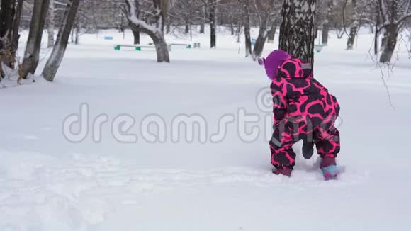 一个穿着粉红色冬季连衣裙的小女孩玩雪视频的预览图