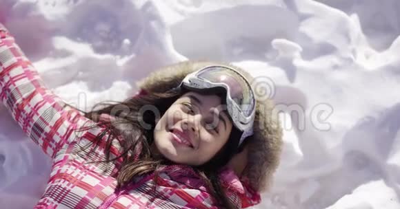 躺在雪地上戴滑雪护目镜的年轻女子视频的预览图