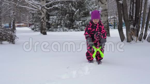 一个穿着粉红色冬季连衣裙的小女孩玩雪视频的预览图